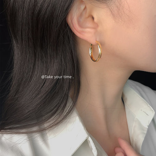 Minimal round-hoop earrings in gold and silver tone shown worn in gold tone.