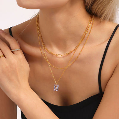 Model wearing gold rectangle zircon pendant necklace layered with chains