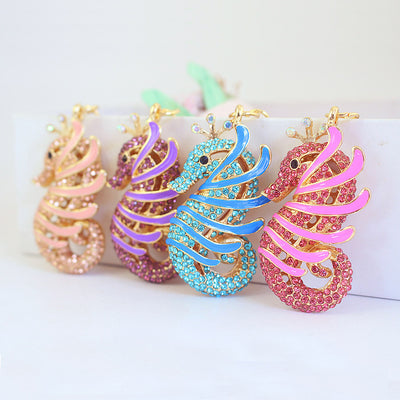 Four rhinestone seahorse charms in peach, purple, blue, and pink stand in a row.