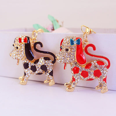 Red and black spotted dog charms stand side by side, each decorated with clear rhinestones and a bow.
