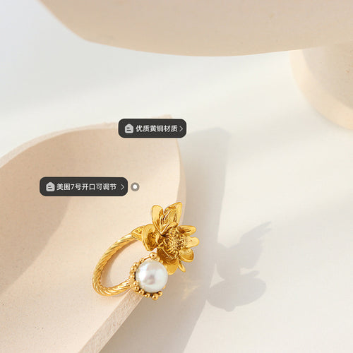 Close gold flower and pearl open ring on beige prop with brass size labels