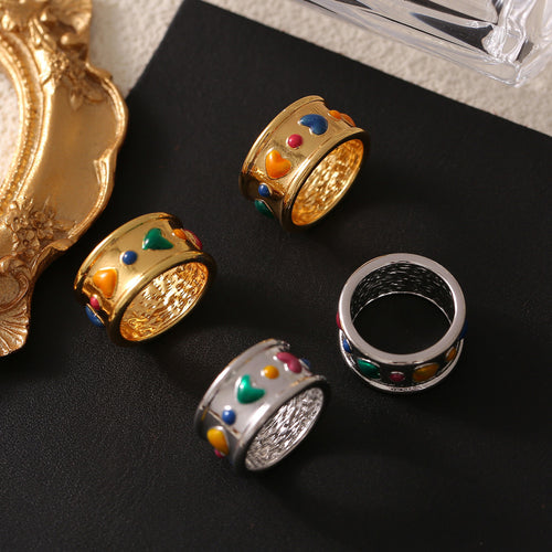 Gold and steel heart oil drip enamel rings on black surface with frame