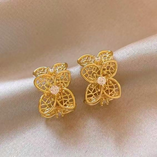 Styled view of openwork four-petal floral hoops in two metal finishes