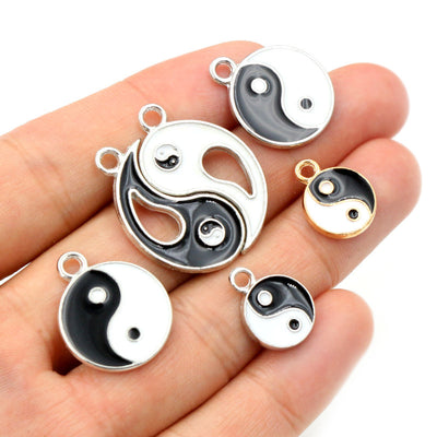 Black and white enamel yin-yang charm with a top loop in a group view on a white background