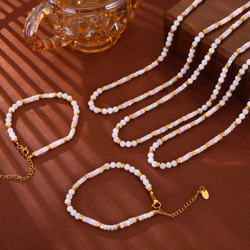 Shell bead necklaces and bracelets with gold spacers on brown surface