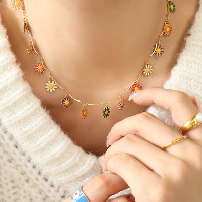 Model wearing gold multicolor enamel daisy charm necklace with cream sweater