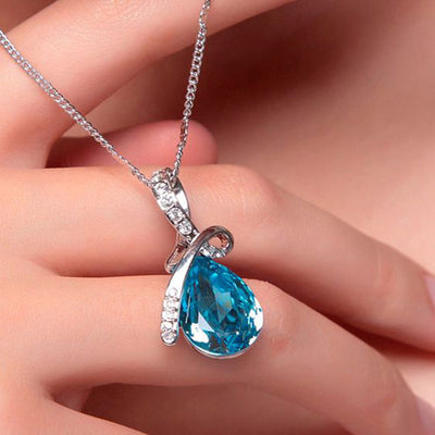 Blue pear pendant held between fingers on silver chain