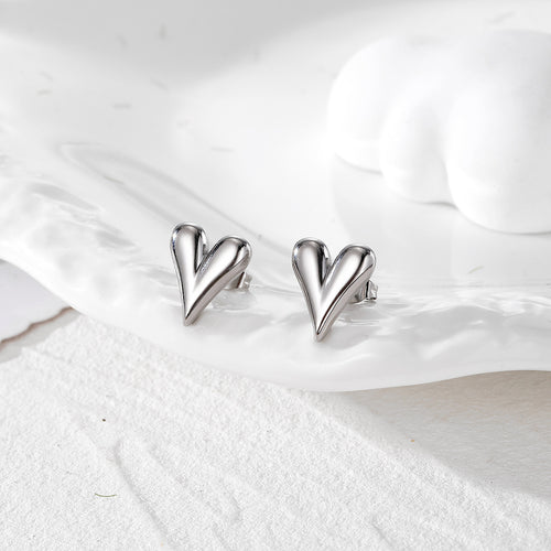 Silver polished dimensional heart stud earrings on white dish