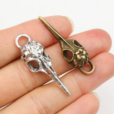 bird-skull charm with a long beak and scissor-like silhouette assortment on a light background
