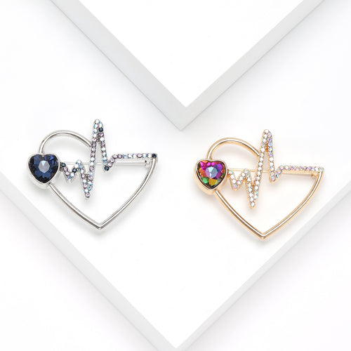 Silver and gold heart electrocardiogram brooches on white stepped blocks