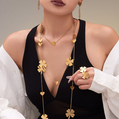 Model wearing long gold clover station necklace and ring