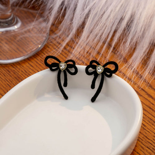 Black velvet bow heart crystal studs on white dish with fur