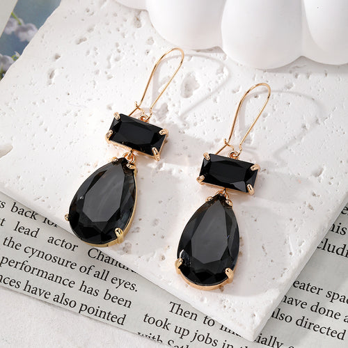Black rectangle and teardrop crystal dangle earrings on white stone
