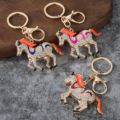 Three rhinestone running horse keychains with colored saddles