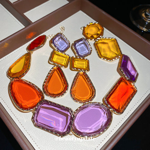 Gold geometric resin necklace and earrings laid in brown box