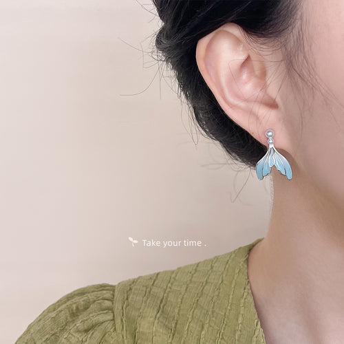 Silver-tone pale-aqua fishtail pearl-like drops shown worn on an ear.