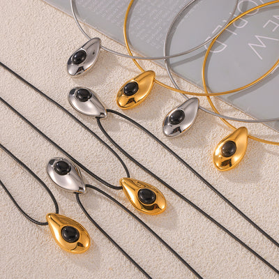 Gold and steel teardrop black stone pendants on cords and snake chains flat lay
