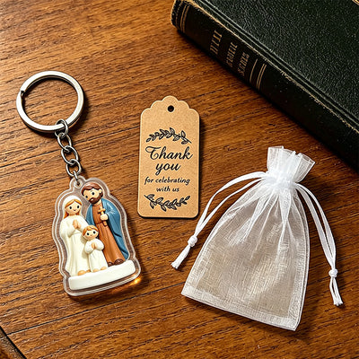 Holy Family keychain beside a printed thank you tag and white drawstring pouch on a wooden table.