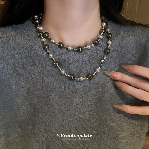 Double strand gray silver pearl necklace worn on gray sweater