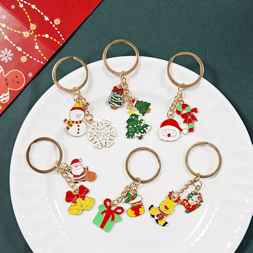 Five gold Christmas keychains with snowman trees Santa gift and reindeer charms on white plate