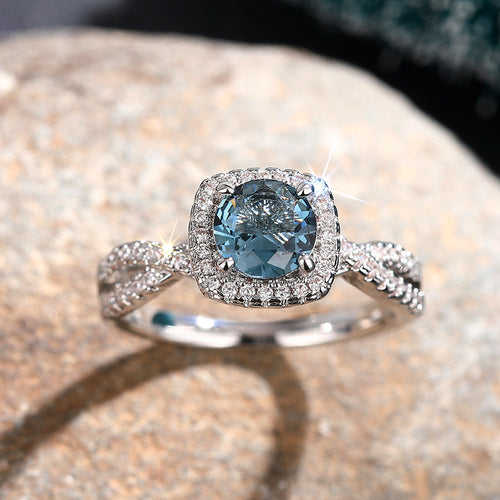 Front view of teal center halo ring on stone surface with sparkle
