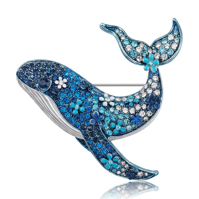 Blue Whale, Pink Whale, Green Whale brooch styles arranged on a light display