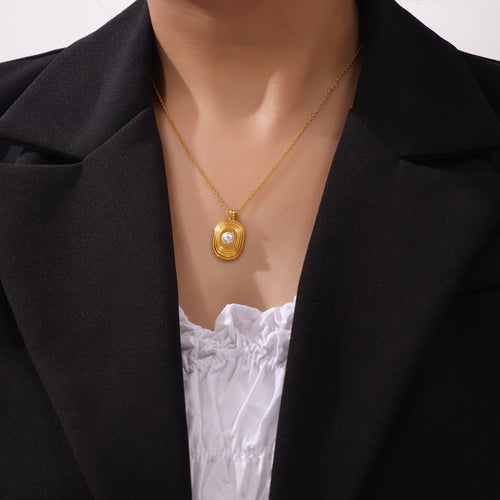 Gold concentric oval pearl pendant necklace worn with blazer