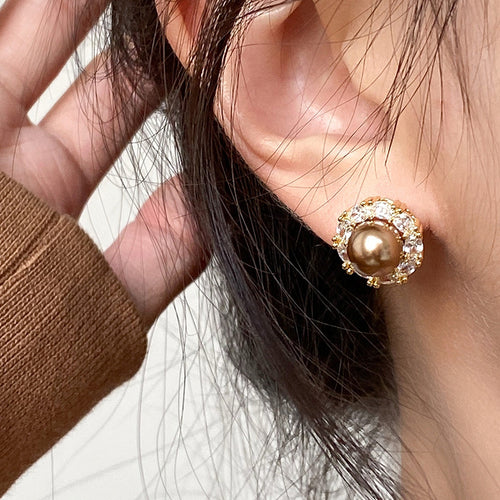 Styled wear view of brown pearl-like centers framed by clear crystals in round gold-tone settings