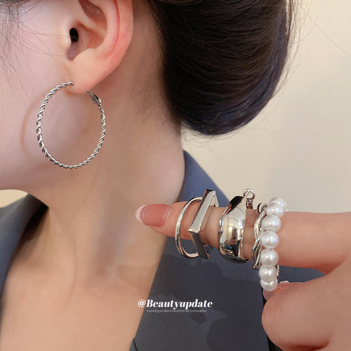 Silver twisted rope hoop worn with other silver hoops held in hand