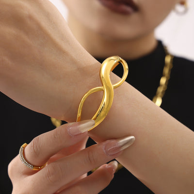 Model wearing gold figure-eight curve clasp bangle close-up