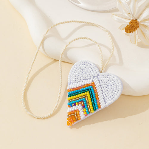 White beaded heart charm with colorful chevron design on a cream cord