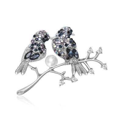 Front view of the two birds on branch brooch in two colorways with polished metal detail on a white background