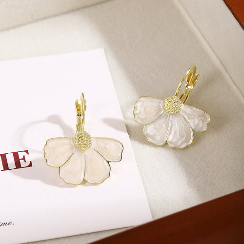 Pair of white enamel gold leverback flower earrings on card in tray