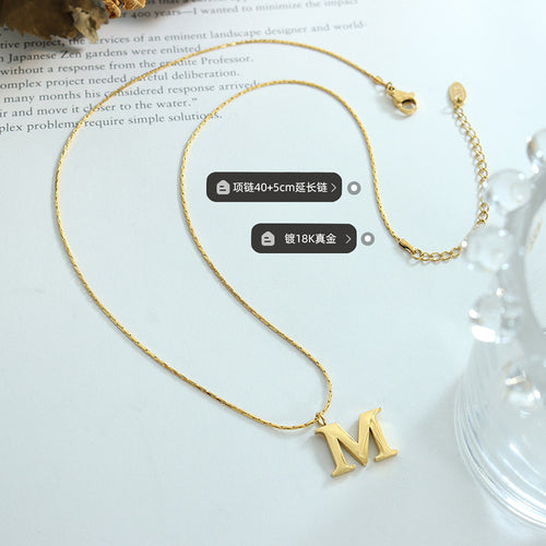Gold M pendant with clasp and extender plus length and plating labels