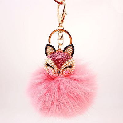 Front view of a beaded pink fox face above a pale pink fluffy pom pom.