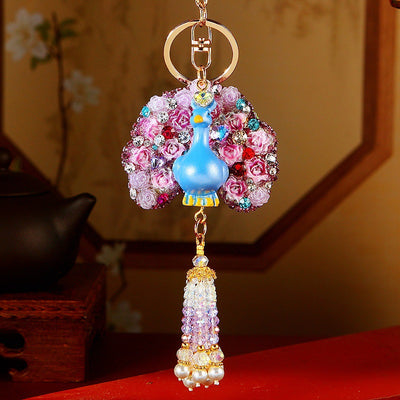 A styled front view shows the floral peacock keychain and its attached hardware.