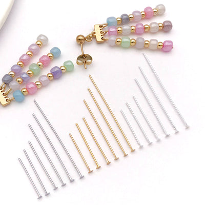 Gold-tone eye pin jewelry findings arranged on a light background