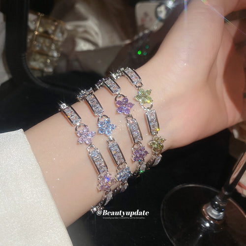 Four silver flower crystal bracelets stacked on wrist in pink purple blue green