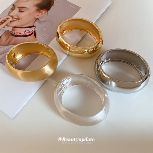 matte gold, polished gold, silver-tone, and clear wide oval bangles grouped together
