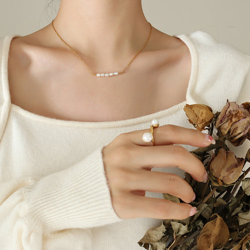 Gold pearl bar station necklace worn on model in cream sweater