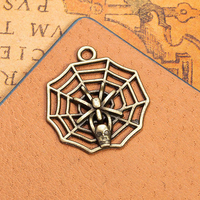 An openwork spiderweb charm centered by a small raised skull motif shown in the main product image