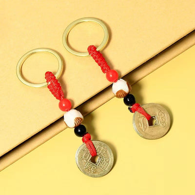 Two red cord keychains with colored beads and opposite sides of round coin pendants.
