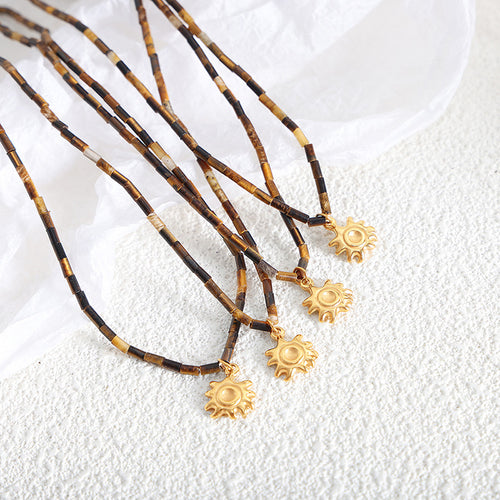 Several tiger eye sun pendant necklaces laid on white textured surface