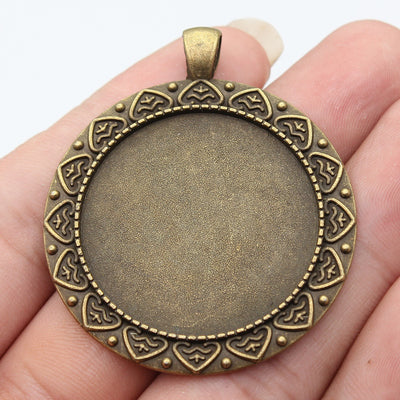 Front view of antique bronze ornate round cabochon setting on fingertips