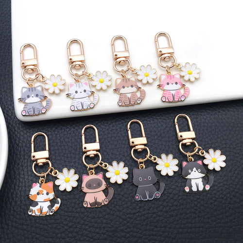 Styled close-up of mixed cat and white daisy enamel clip keychain eight-style showing colors and surface details