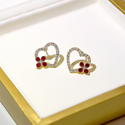 Gold open heart crystal studs with red flower accents in white jewelry box