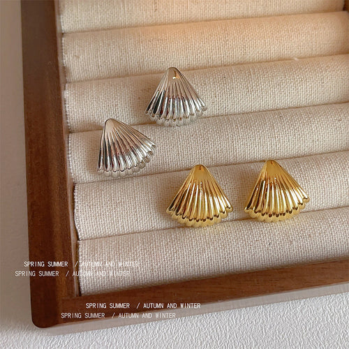 Ridged shell-fan stud earrings in gold and silver tone displayed as both colors.