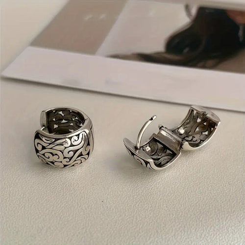Antique silver wide swirl huggie pair open and closed on table