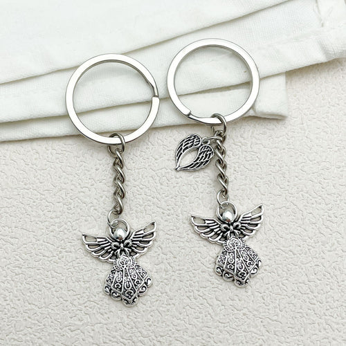 Image 2 showing a pair of silver angel charms on top of white cloth.