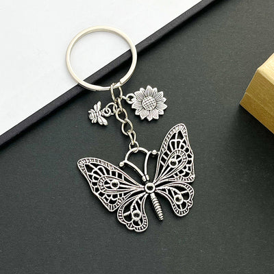 Front product photo of antique silver openwork butterfly bee and sunflower charm keychain showing the pictured design ar